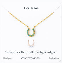 Load image into Gallery viewer, Gold horseshoe necklace with turquoise stones on a white background, featuring a quote and Veravara branding.
